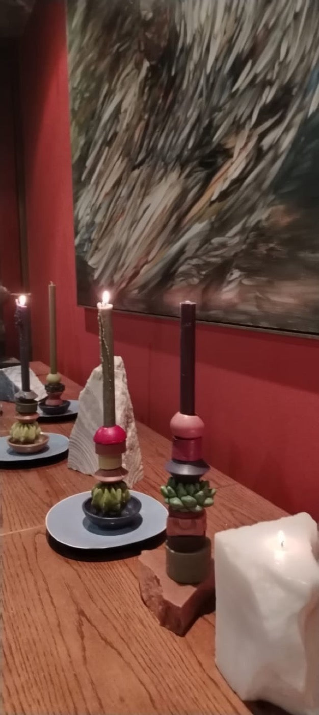 Two stacked candles in olive and rose tones on a candlelit table
