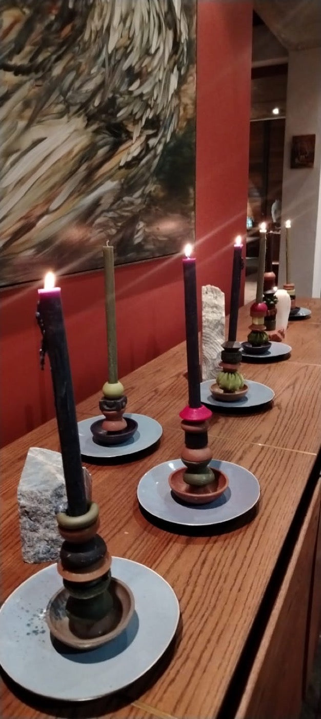 Lit stacked candles in earthy tones running down a wooden table