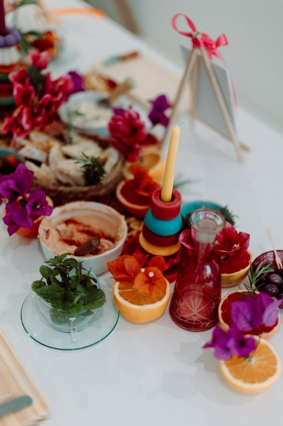 Red and teal stacked candle beside citrus, mint and bougainvillea