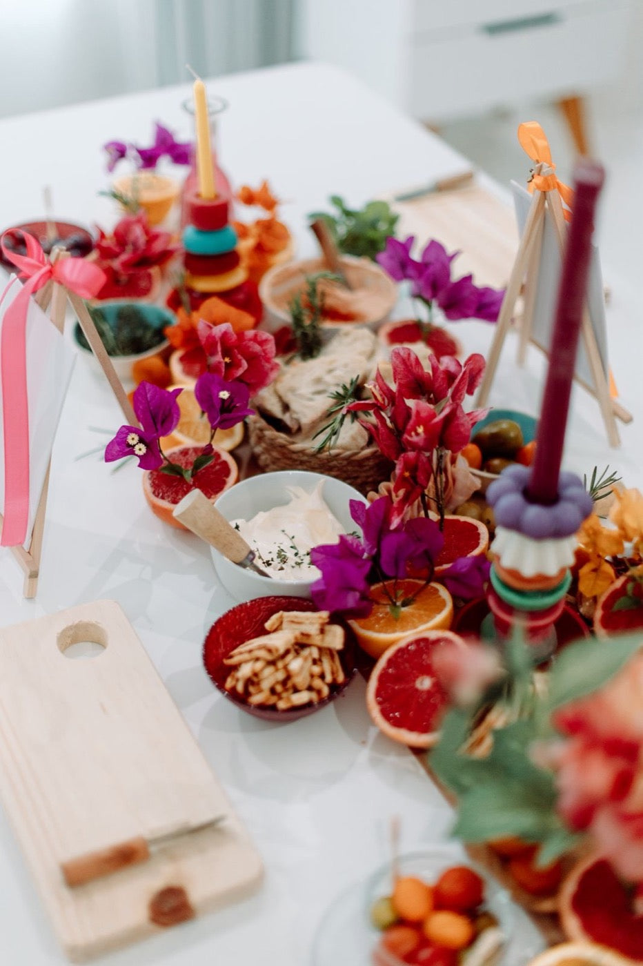 Overhead view of a grazing table with two stacked candles among flowers and dips