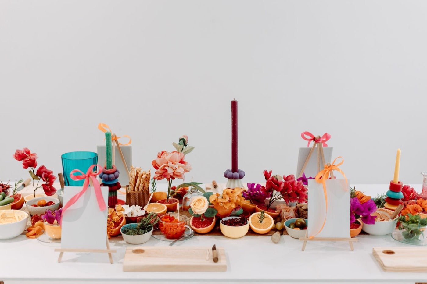 Grazing table styled with stacked candles, citrus and bougainvillea