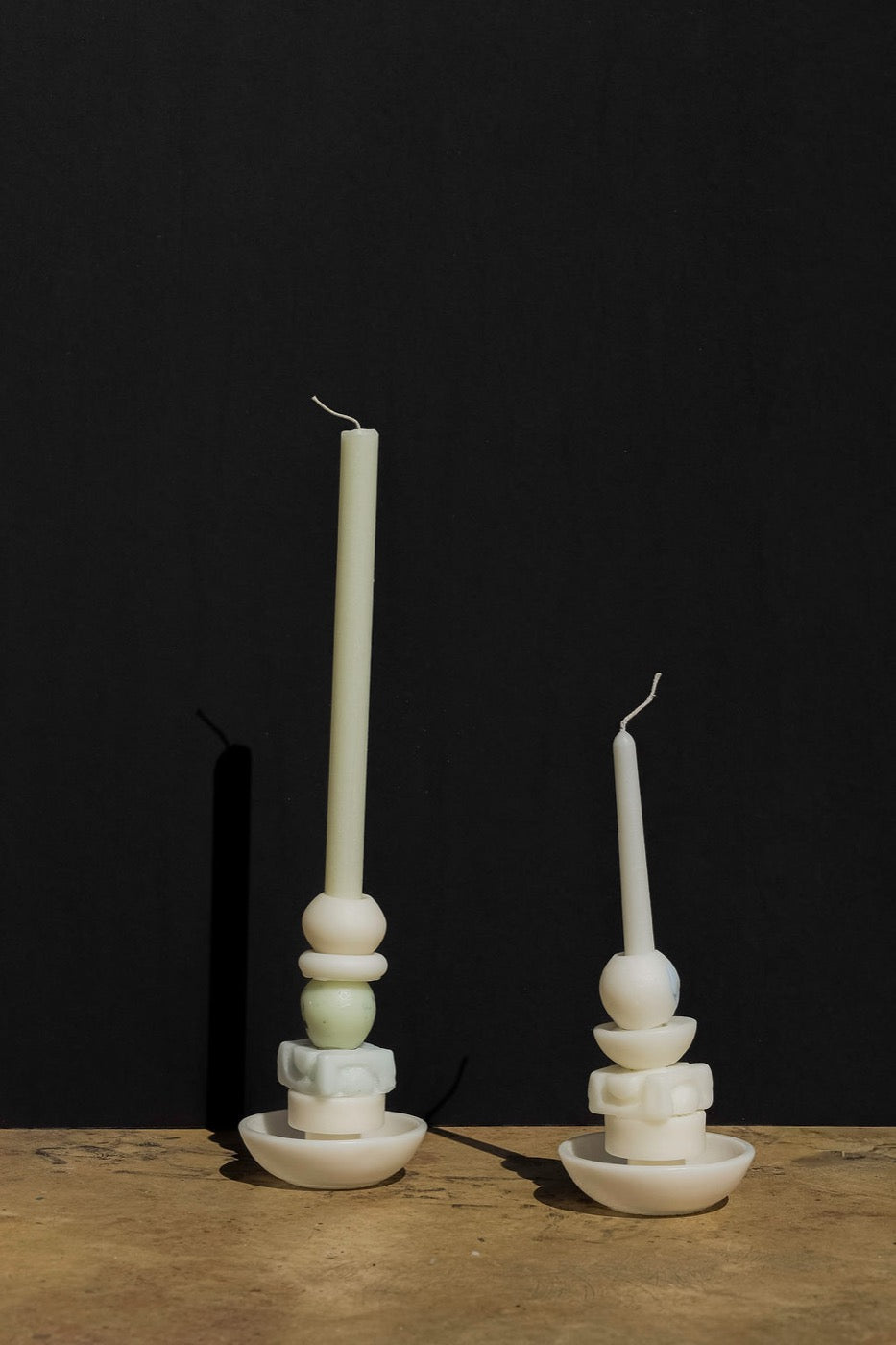 Pair of cream stacked candles with pale green spheres on a black backdrop
