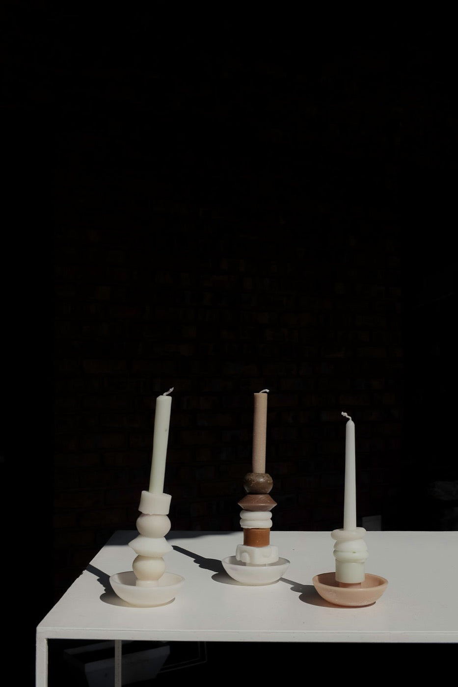 Three cream and terracotta stacked candles on a white table