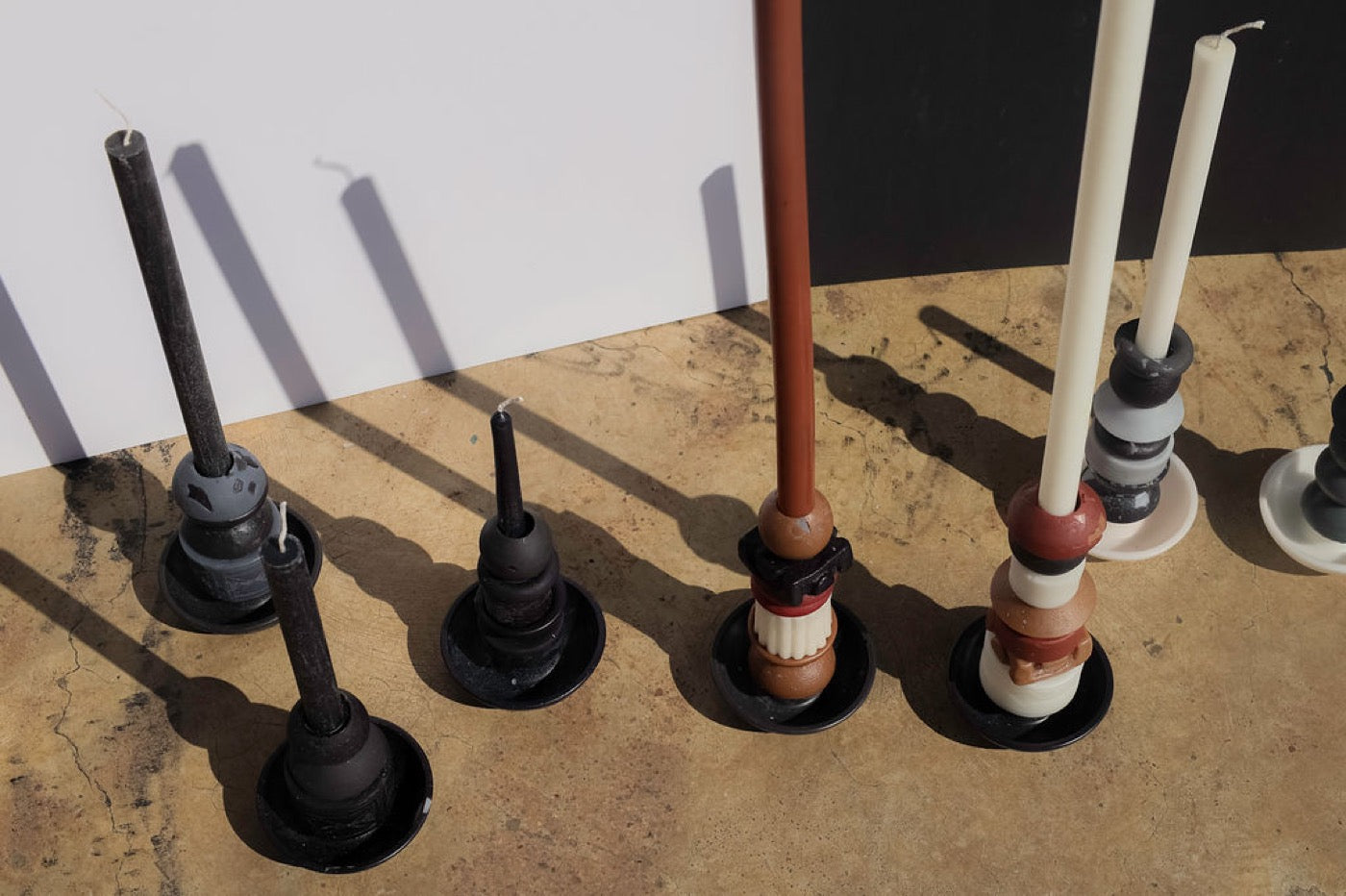 Overhead row of dark stacked candles with long shadows