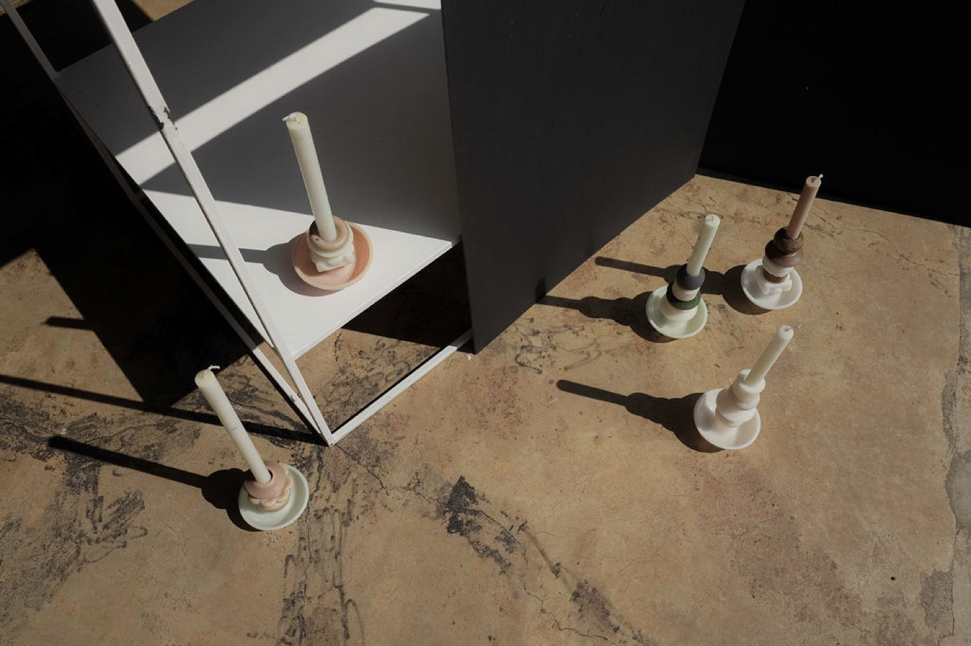 Overhead view of five candle holders arranged around a white plinth
