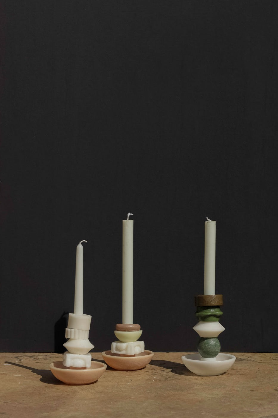 Three ivory and green stacked candles in terracotta and white bowls