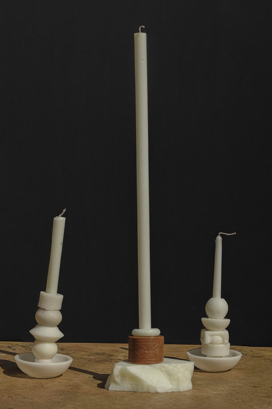 Three ivory stacked candles of varying heights against a black backdrop