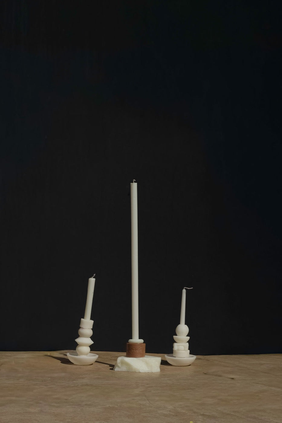 Ivory taper on a terracotta ring atop a wax slab, flanked by two stacks