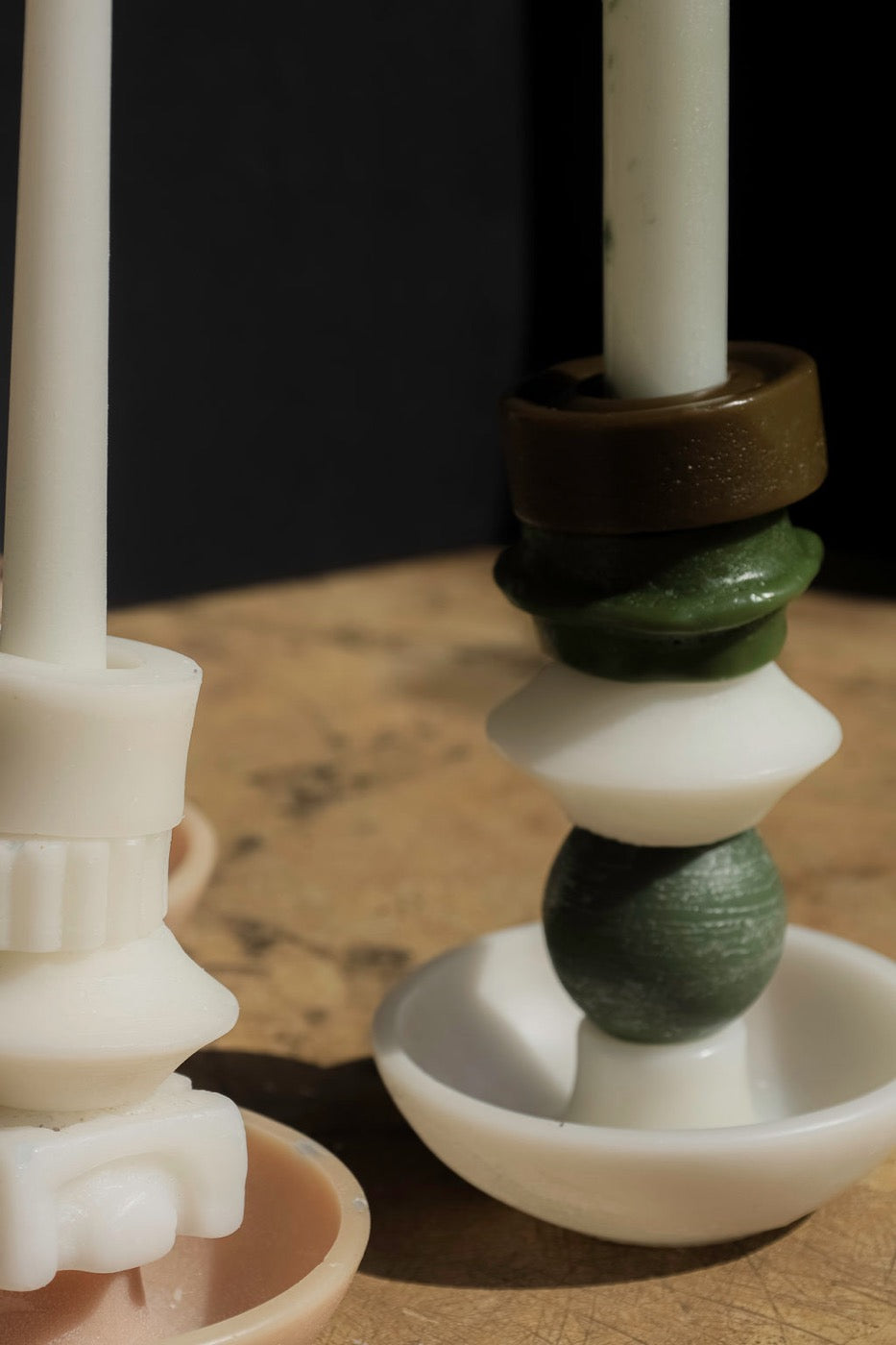 Close-up of an olive and green stacked candle beside a white one