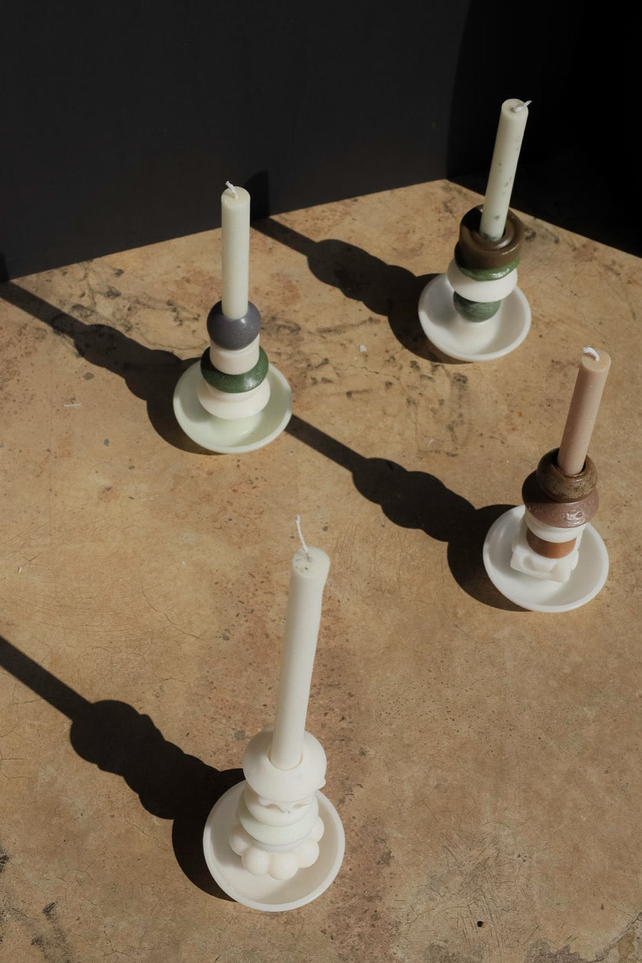 Overhead view of four pale stacked candles casting long shadows