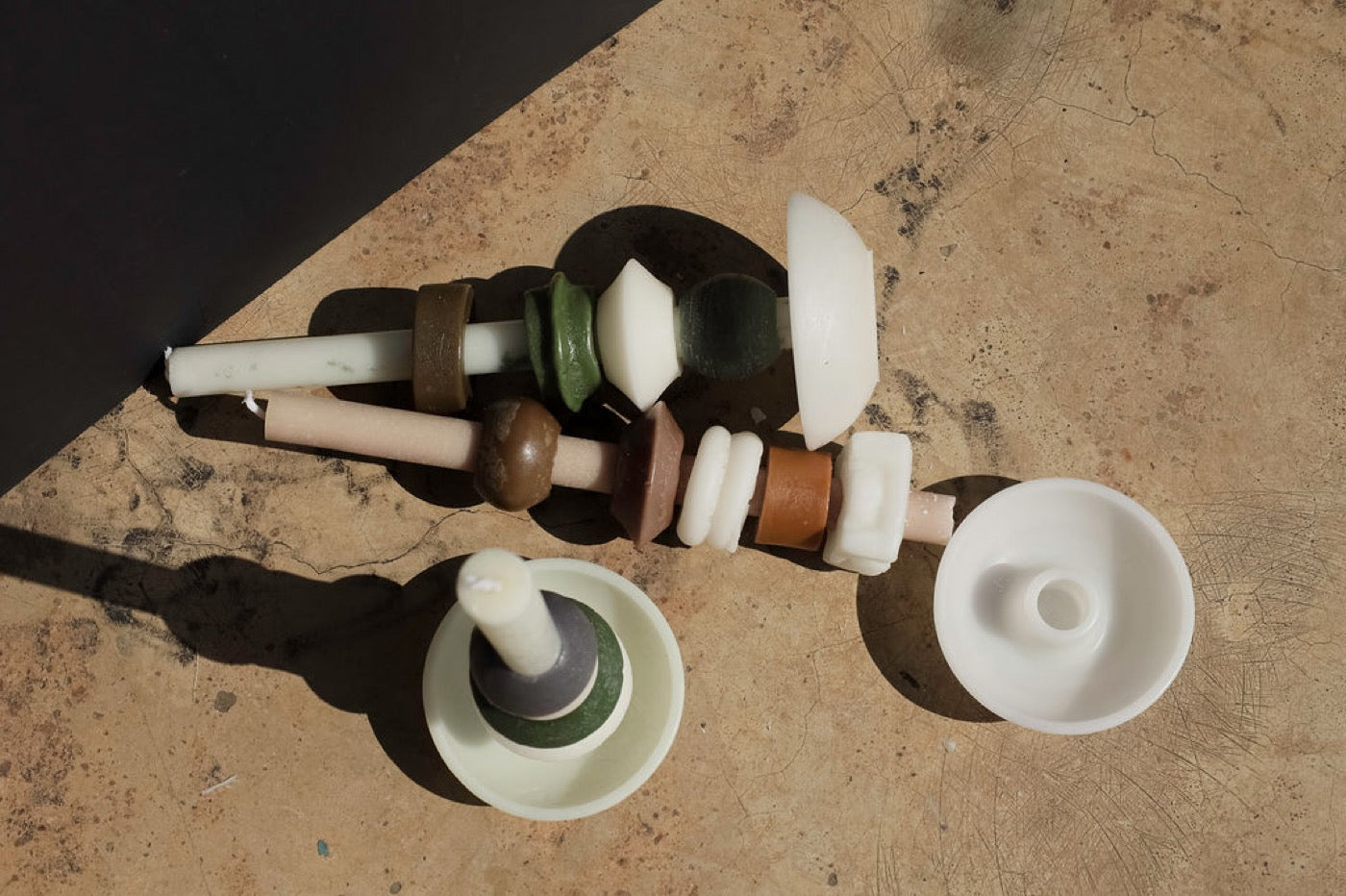 Flat lay of stackable candle pieces and tapers on sunlit concrete