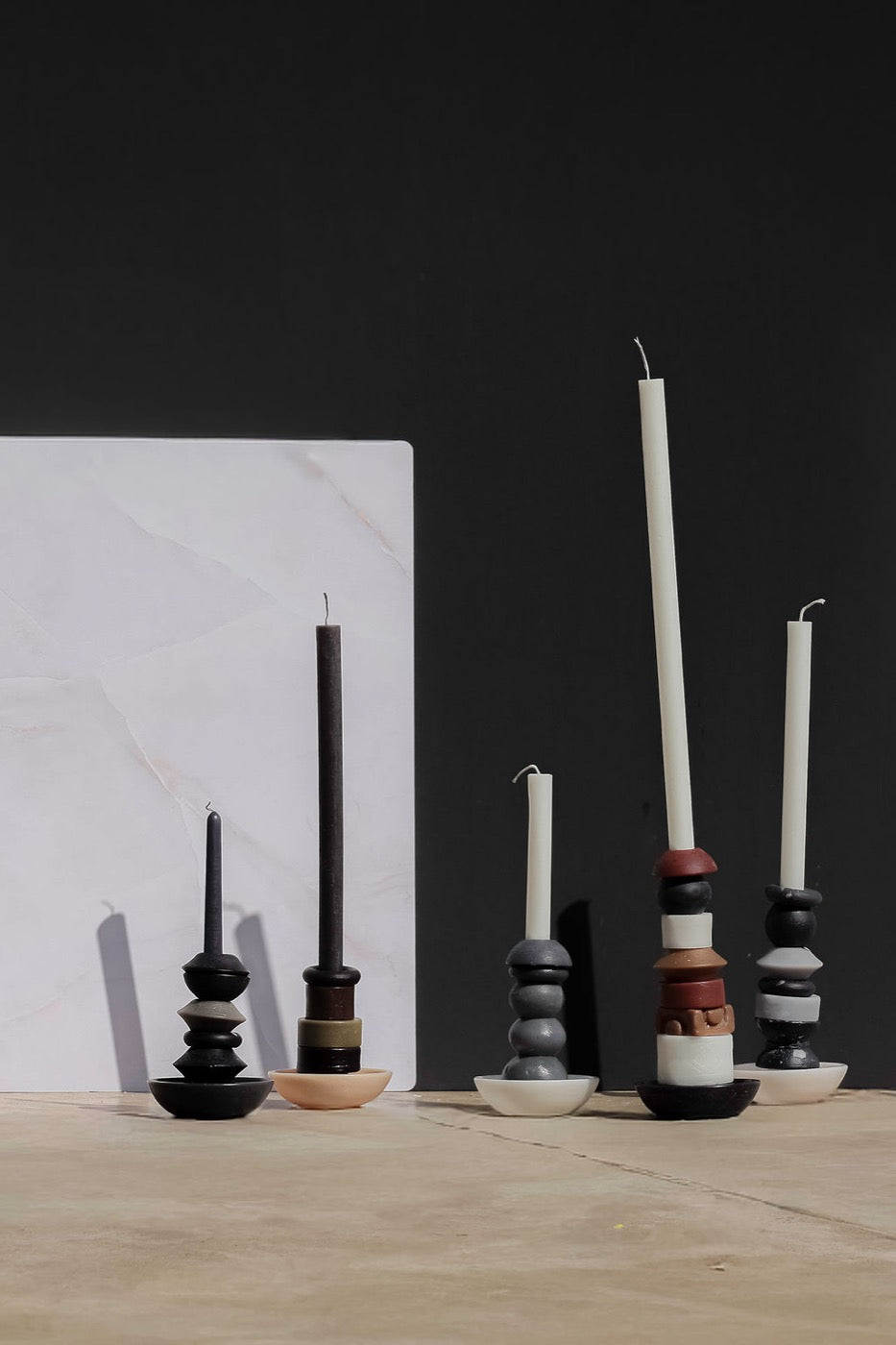 Five stacked candles lined up beside a marble panel